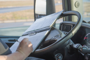 Closeup view of the hands of truck driver who is is writing in the documentation driver.